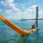 Young man relaxing in hammock suspened in the beautiful freshwater of the Bacalar Lagoon.