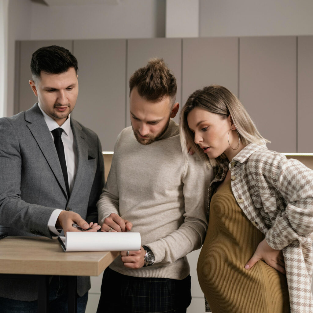 Real estate agent meeting with milennial couple showing a house or apartment on laptop